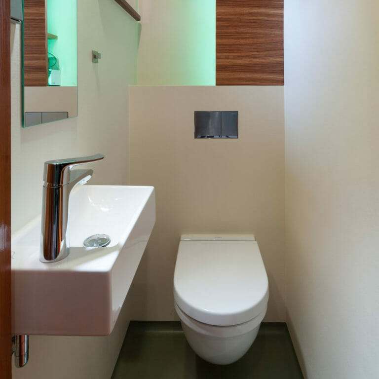 Stauraumregal in Zebrano Furnier mit LED in Niesche oberhalb der Toilettenvorwandinstalation in Gäste WC