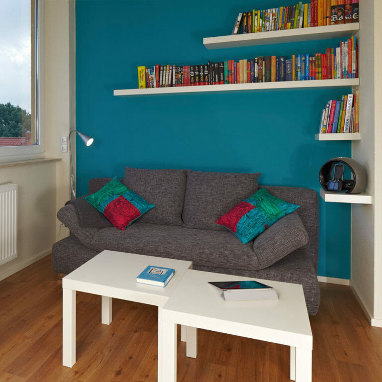 Leseecke mit Tablarböden als Bücherregal über Sofa